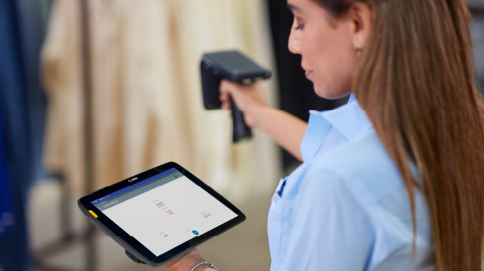 Woman looks at tablet screen while using handheld scanner.