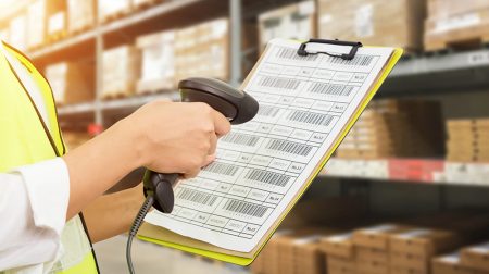 Handheld scanner reads a barcode for an employee on a clipboard.