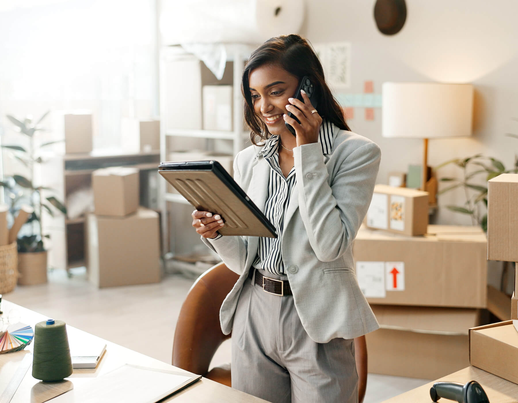 Woman smiles while talking on her phone and using her tablet.