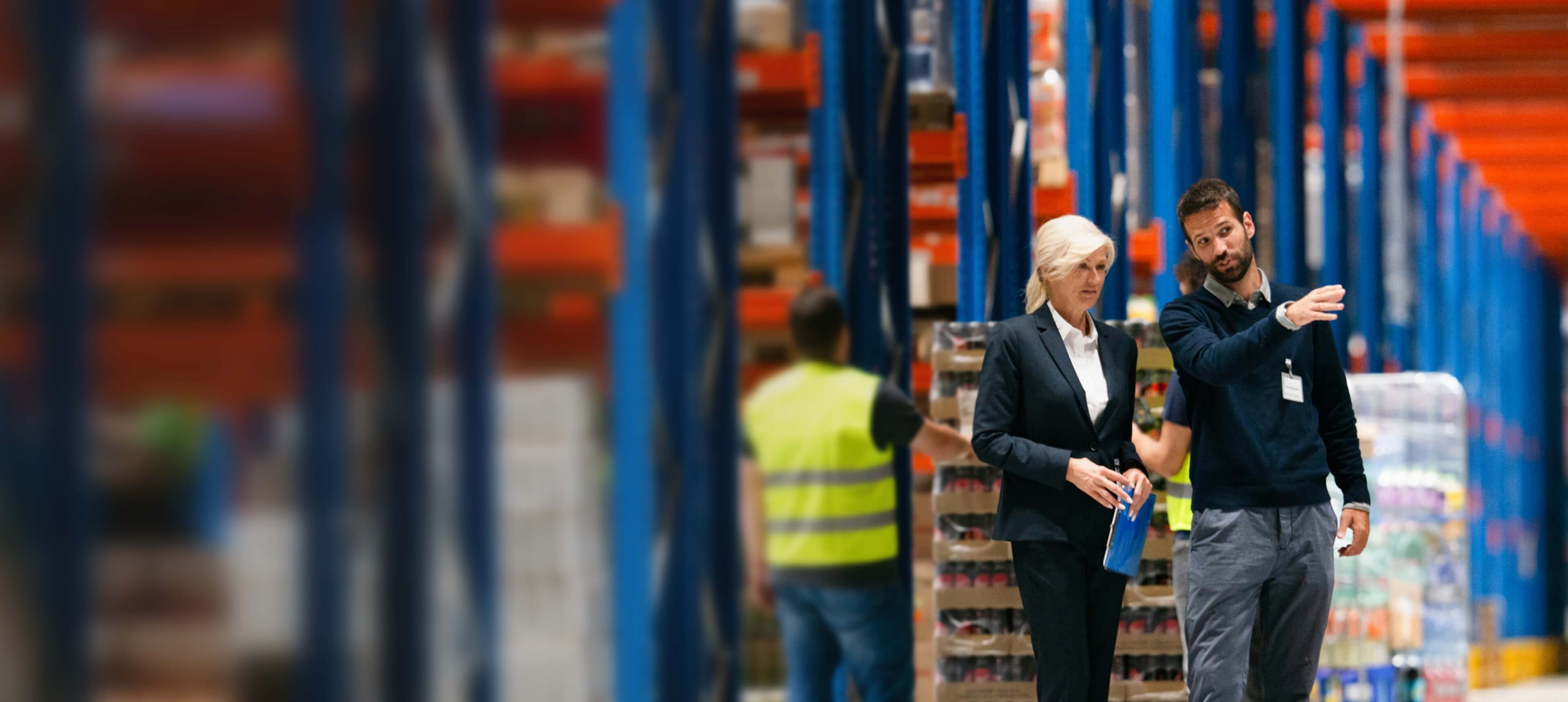 Two people walk through a brightly lit warehouse, discussing how DecisionPoint can help them.