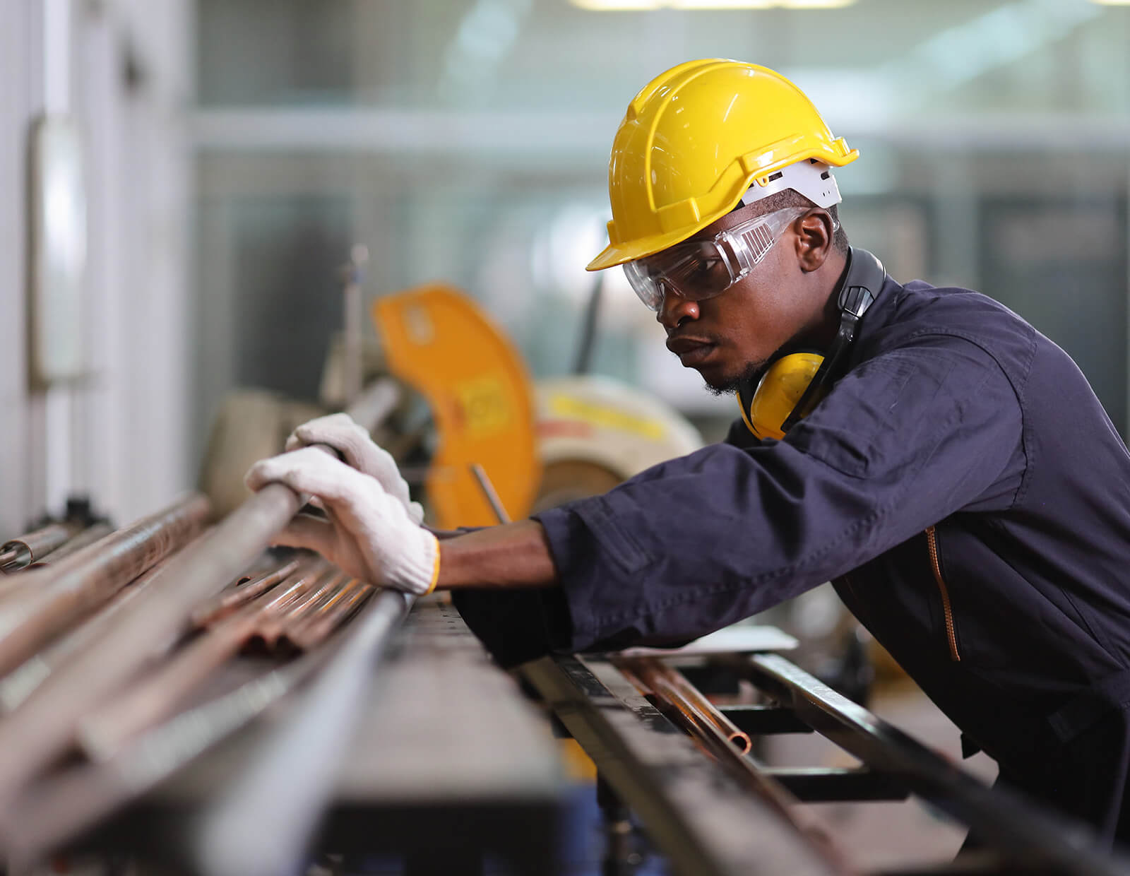 Man cuts metal pipes in the manufacturing industry.