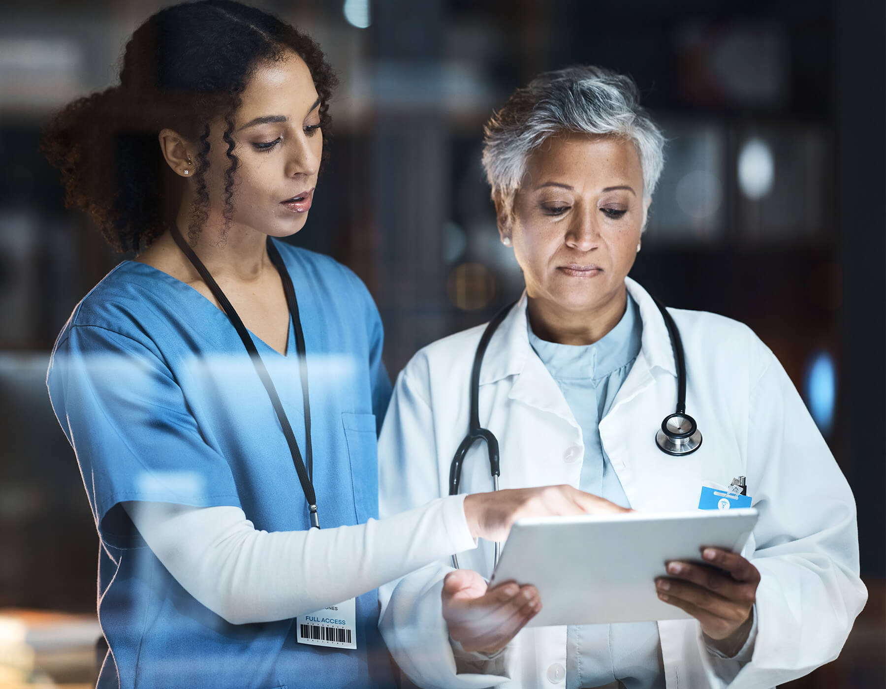Nurse discusses patient information held by a doctor on their tablet.
