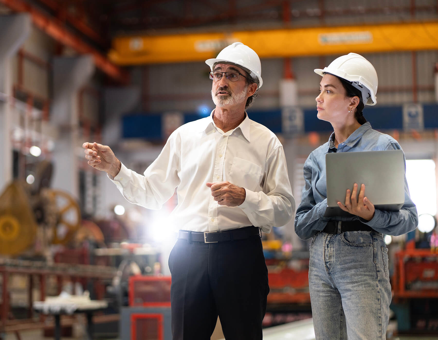 Manufacturing plant workers discuss the day while using a laptop.