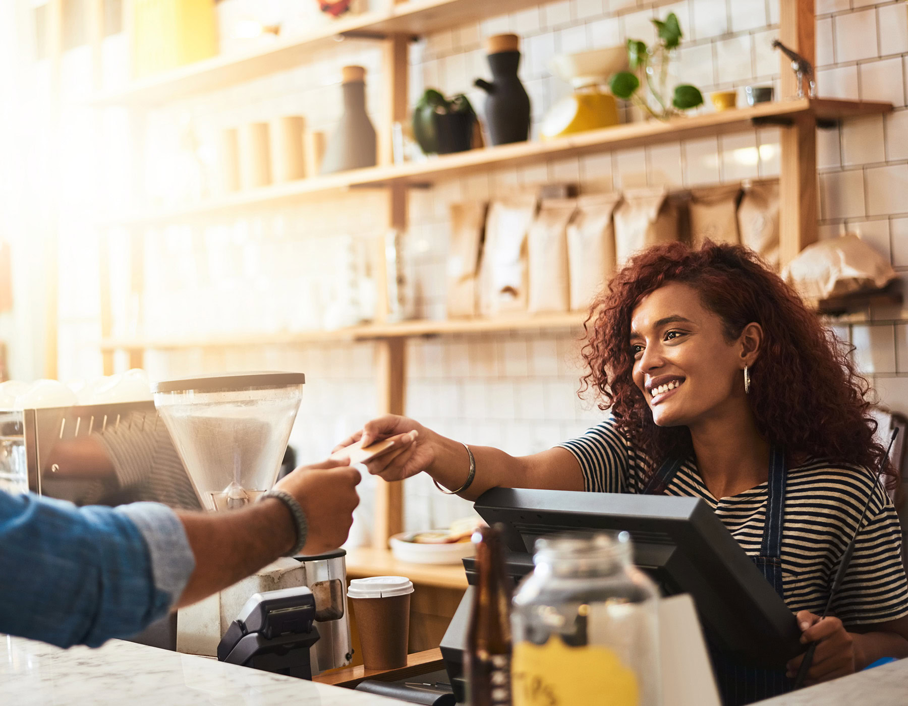 Restaurant employee smiles while she takes a customer card to use with her POS terminal.