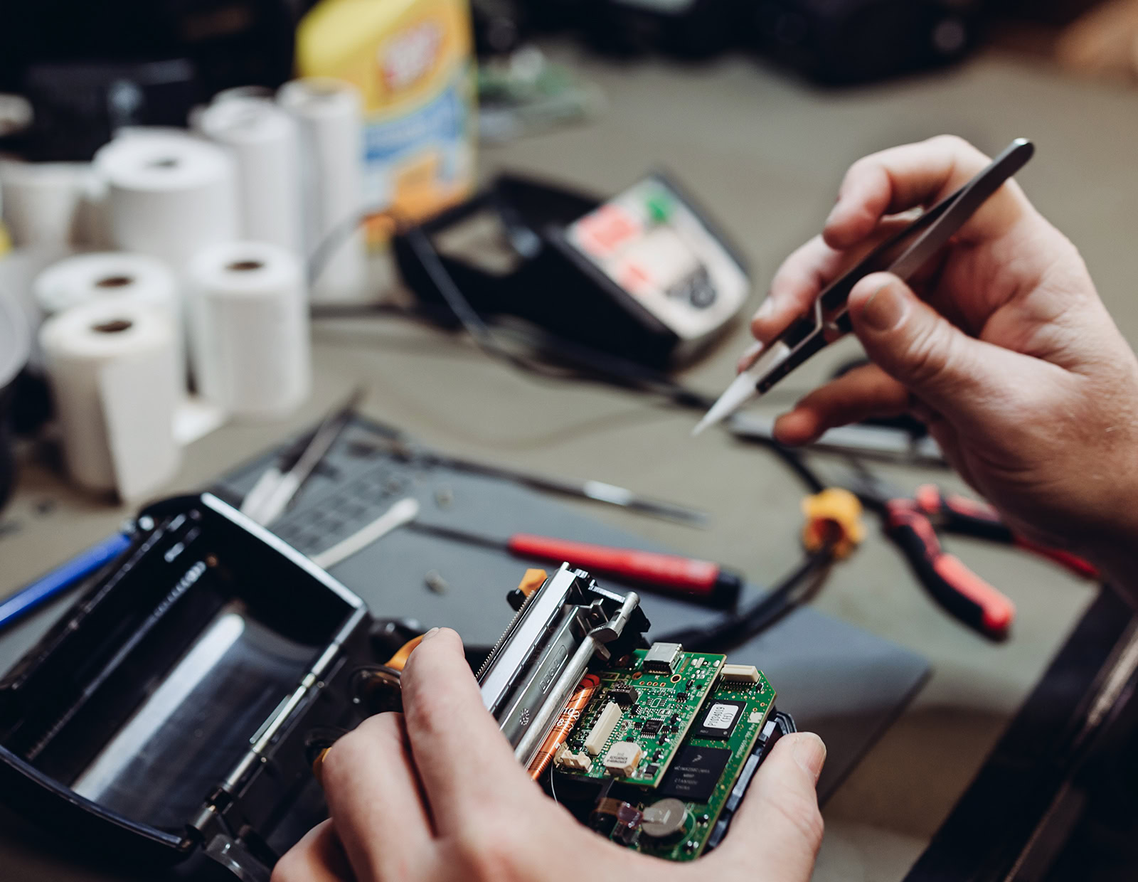 Technician works on a handheld rental unit, using specialized tools.