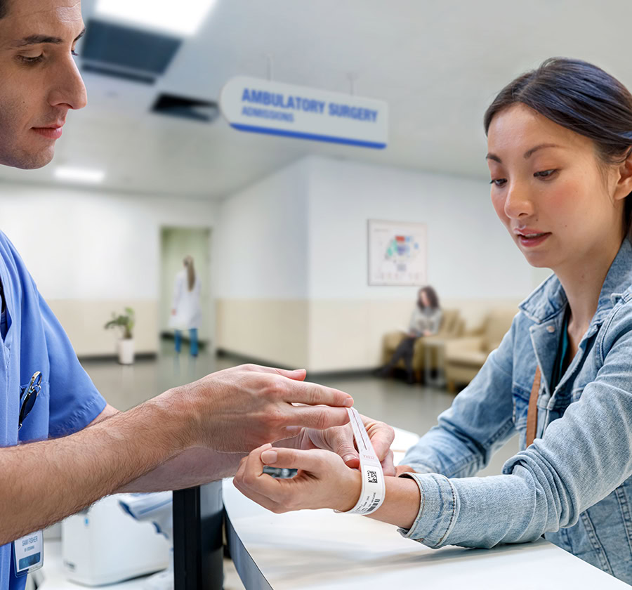 Healthcare worker places a band on a patient with a QR code that ensures continuity of care.