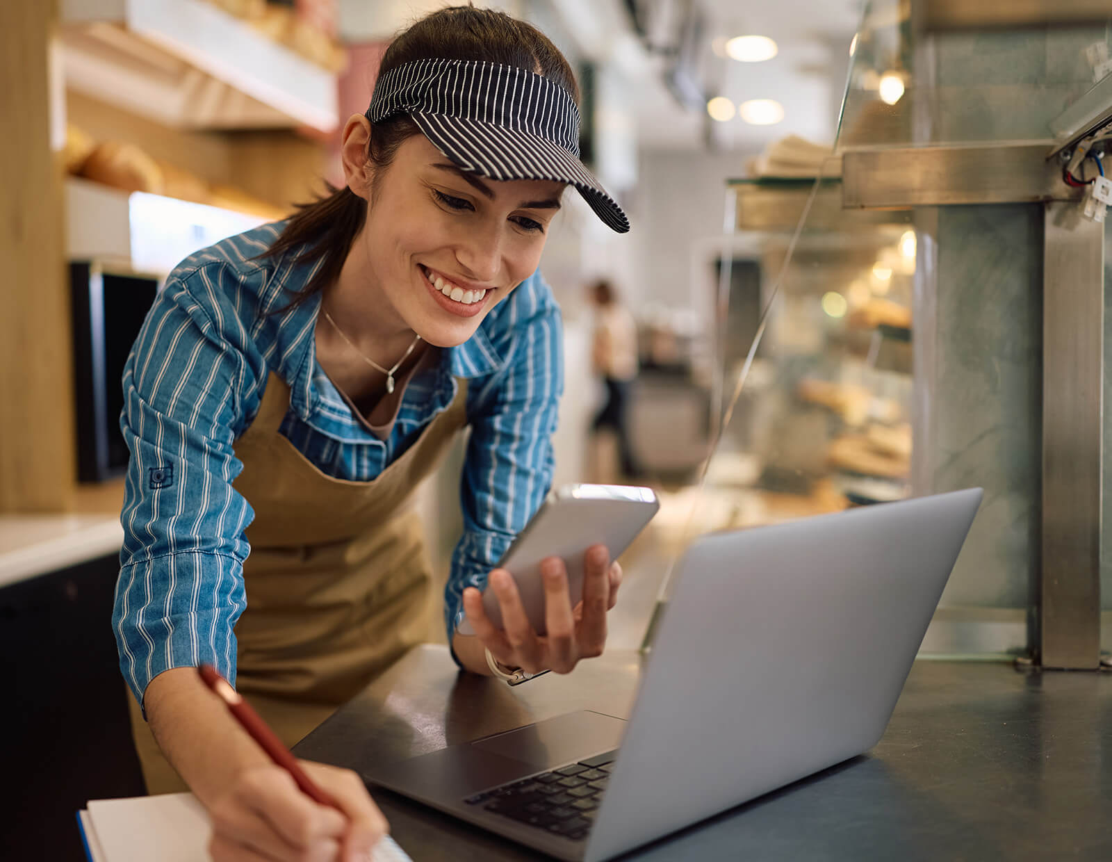 Restaurant employee tracks with VeriMy software, smiling while checking her mobile device.