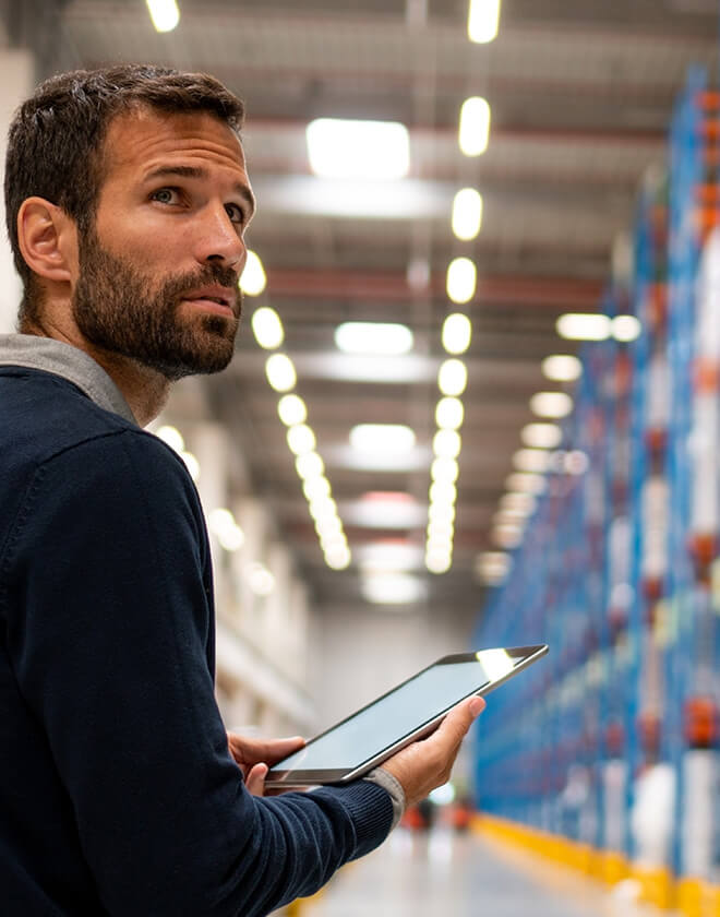 Man with a tablet tracks everything he needs to know while exploring a warehouse.