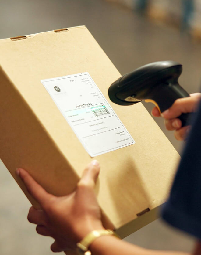 Person uses a handheld scanner to handle a package, scanning the barcode.