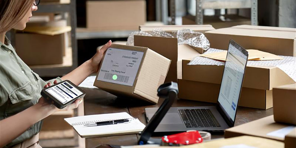 A woman employee scans a barcode with a Datalogic memory device with a mobile device.