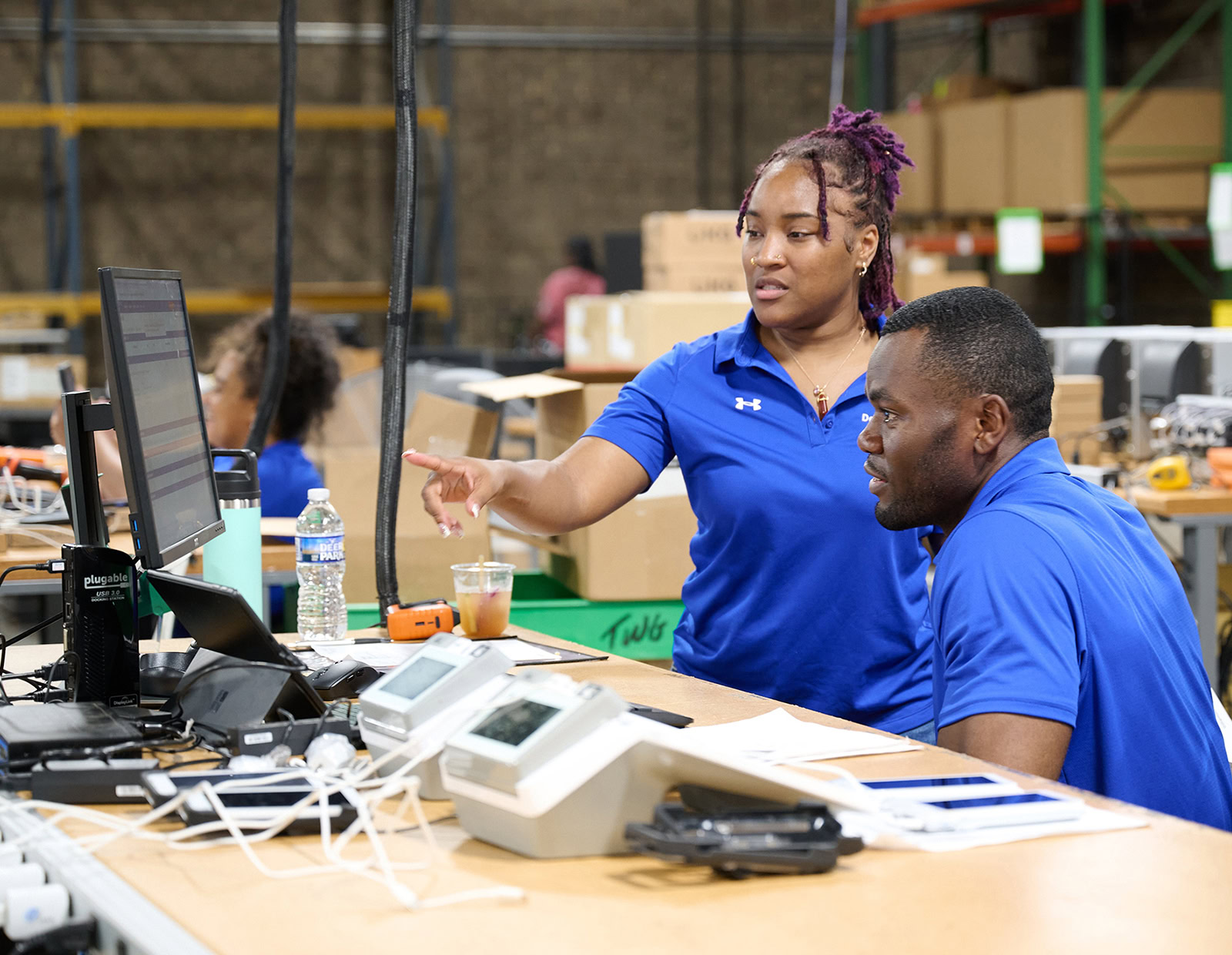 DecisionPoint employees prepare for a deployment, discussing what they see on a computer screen and enjoying their career.