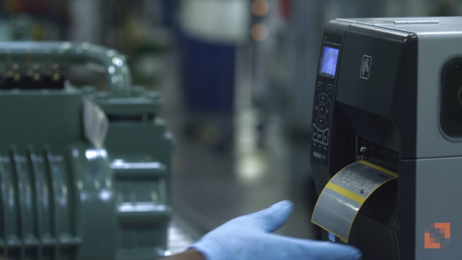 Industrial label printer producing barcode labels in a manufacturing environment, highlighting the importance of print media quality for uptime and operational performance.