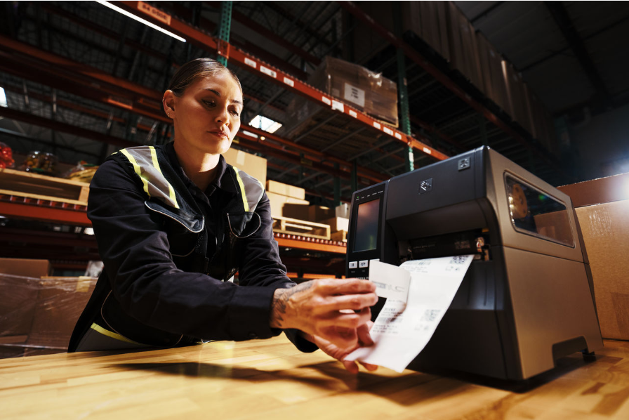 Manufacturing worker collecting printed RFID labels from an industrial label printer